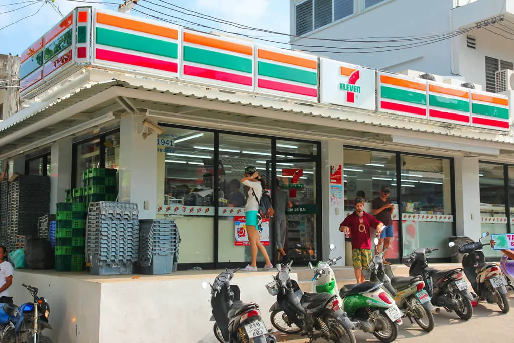 Motorräder und Menschen vor einem 7-Eleven in Thailand
