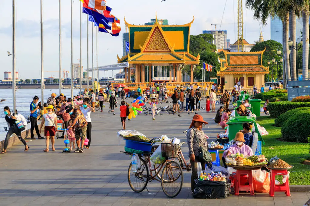 Zahlreiche Menschen und Obstverkäuferinnen am Flussufer in Phnom Penh