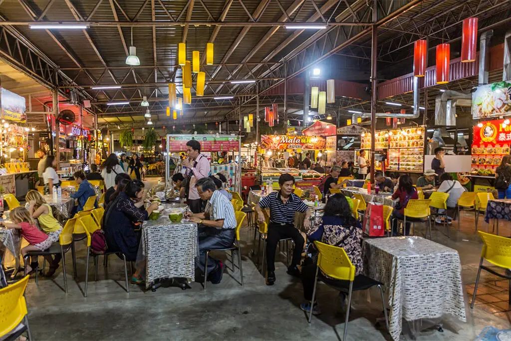 Menschen an kleinen Tischen, die auf einem Nachtmarkt in Chiang Mai essen