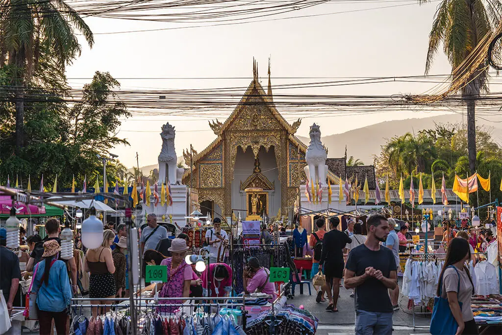 Getummel auf der Sunday Walking Street in Chiang Mai vor einem goldenen Tempel zum Sonnenuntergang