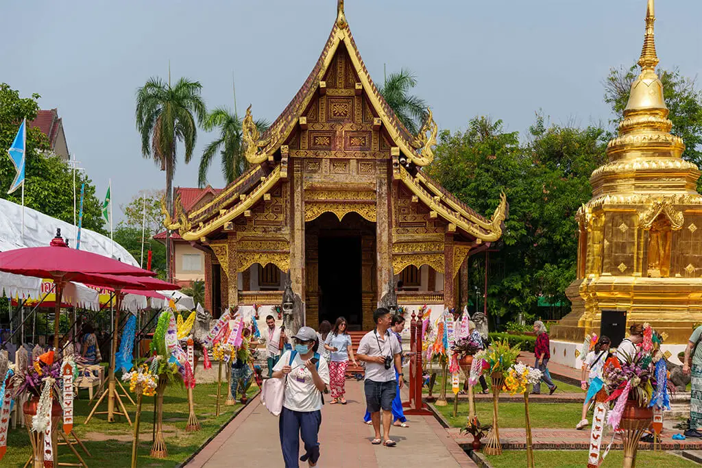 Wat Phra Singh in Chiang Mai mit vielen Besuchern an einem sonnigen Tag mit blauem Himmel