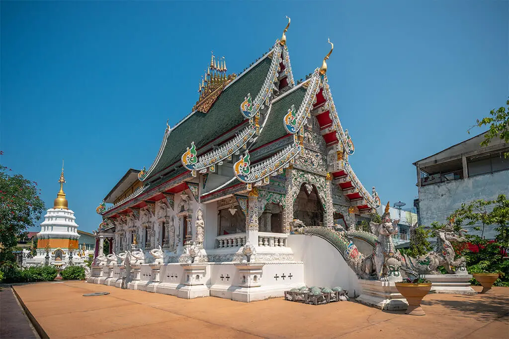 Wat Ming Muang in Chiang Rai mit bunten Verzierungen vor blauem Himmel