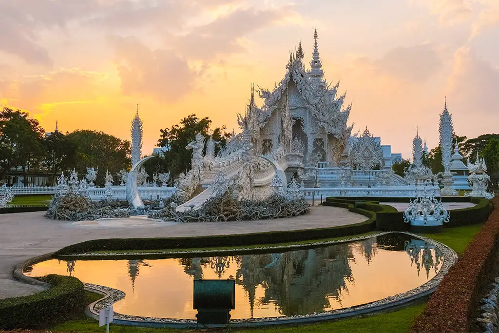 Der Weiße Tempel in Chiang Rai zum Sonnenuntergang mit Spiegelung im Teich