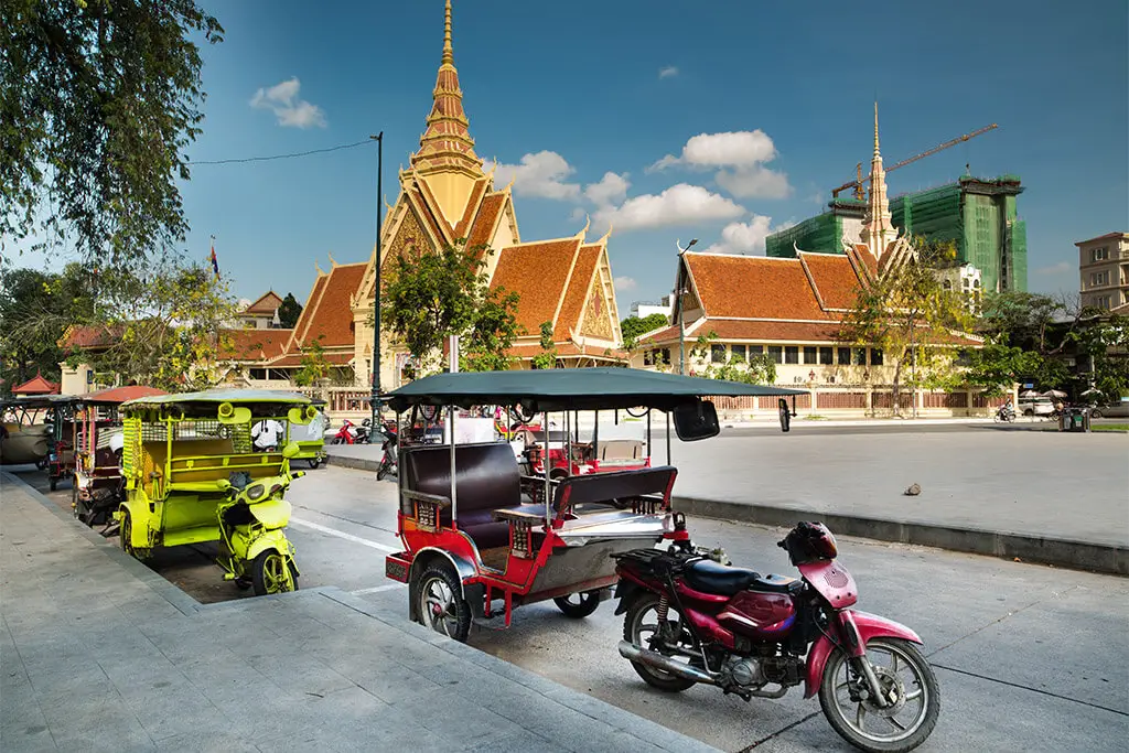 Motorrad und Tuk-Tuks am Straßenrand vor dem Königspalast in Phnom Penh