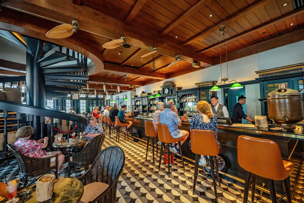 Long Bar im Raffles Hotel in Singapore mit Gästen an der Theke