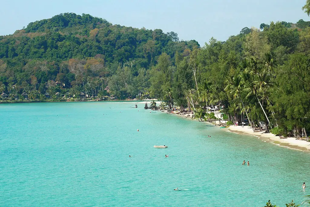 Ruhige Bucht mit Palmen, türkisfarbenem Wasser und badenden Touristen