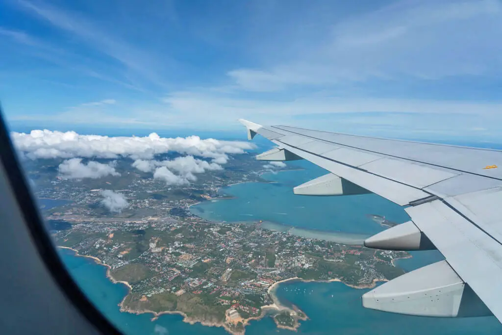Der Blick aus dem Flugzeugfenster zeigt die Insel Koh Samui mit ihren Stränden und hügeligen Landschaft