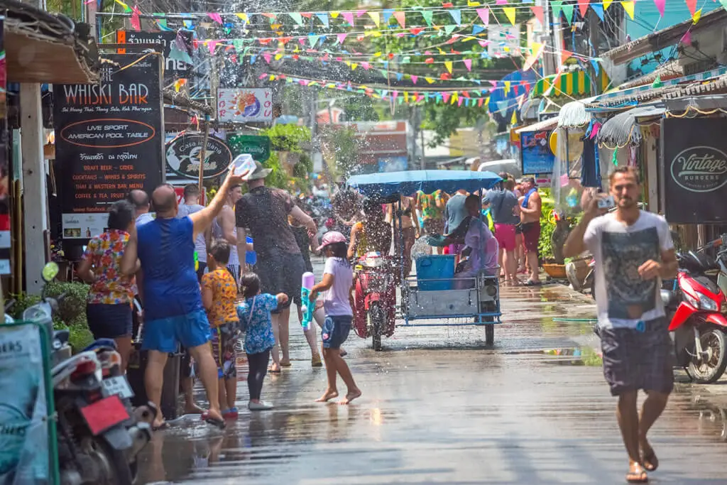 Menschen liefern sich eine wilde Wasserschlacht mit Wasserpistolen und Eimern voller Wasser auf den Straßen von Koh Phangan