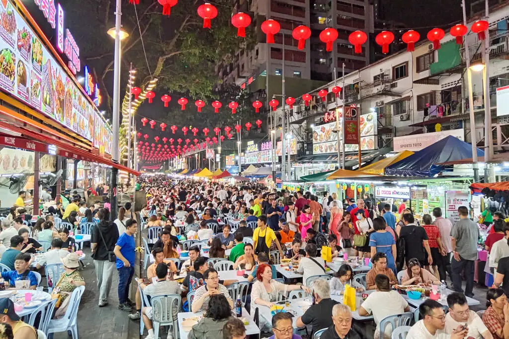 Ein riesiger Streetfoodmarkt mit zahlreichen Tischen, Stühlen und Garküchen sowie hunderte Menschen