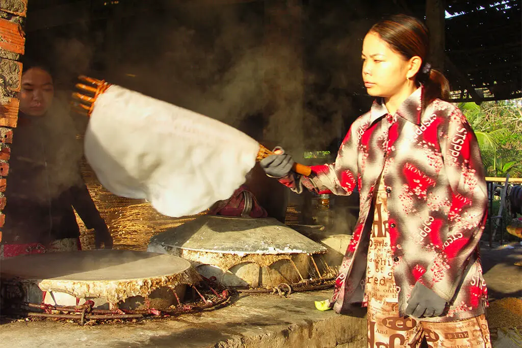 Vietnamesische Frau bei der Herstellung von Reispapier