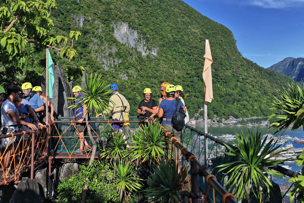 Teilnehmer einer Canopy Tour stehen an einem Aussichtspunkt, sie tragen Helme und Sicherheitsausrüstung, El Nido