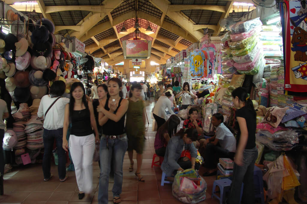 Innenansicht des Ben-Thanh-Marktes mit Menschen und Marktständen.