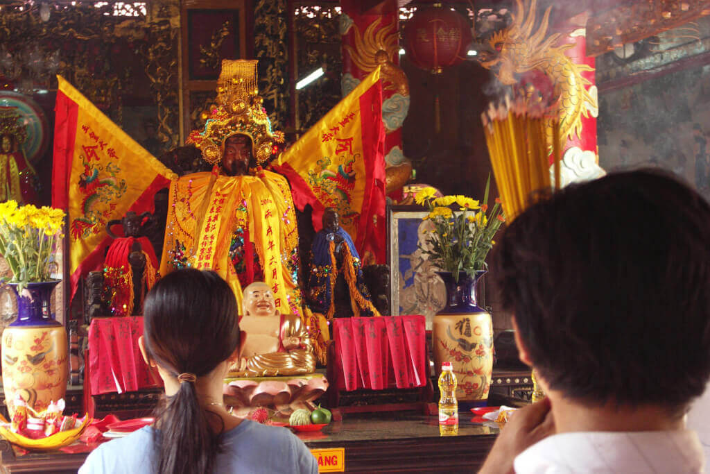 Rückansicht der Köpfe eines Mannes und einer Frau, die vor einem chinesischen Altar beten.