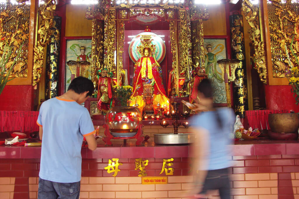 Rückansicht eines Mannes und einer Frau vor einem Altar in einem chinesischen Tempel in der Chinatown in Ho-Chi-Minh-Stadt.