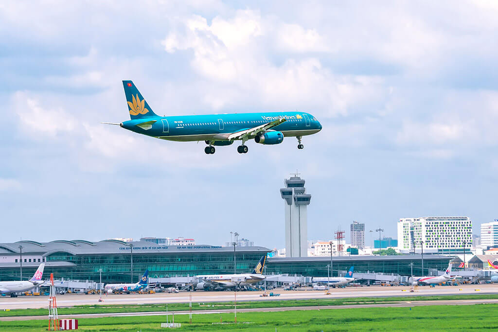 Flugzeug von Vietnam Airlines kurz vor der Landung am Flughafen. Weitere Flugzeuge stehen vor dem Terminal.