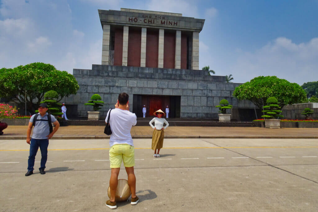 Vor dem Ho-Chi-Minh-Mausoleum, (c) Andrea Markand Ein Tourist fotografiert vor dem Ho-Chi-Minh-Mausoleum in Hanoi eine Touristin, die einen konischen Hut trägt