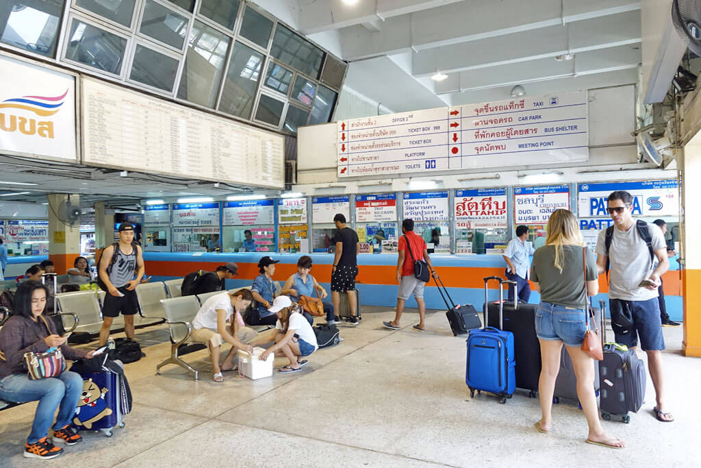 Ein Busbahnhof von innen mit Anzeigetafeln, Ticketschalter und vielen Fahrgästen
