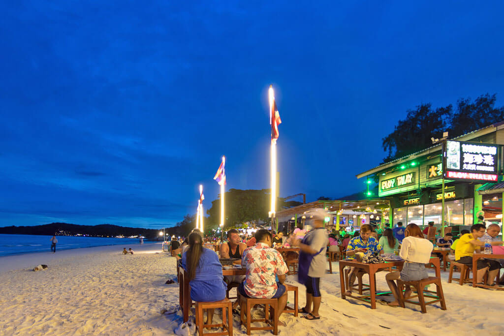 Einige Strandbars- und Restaurants bei Nacht mit vielen Menschen an einem Strand auf Koh Samet