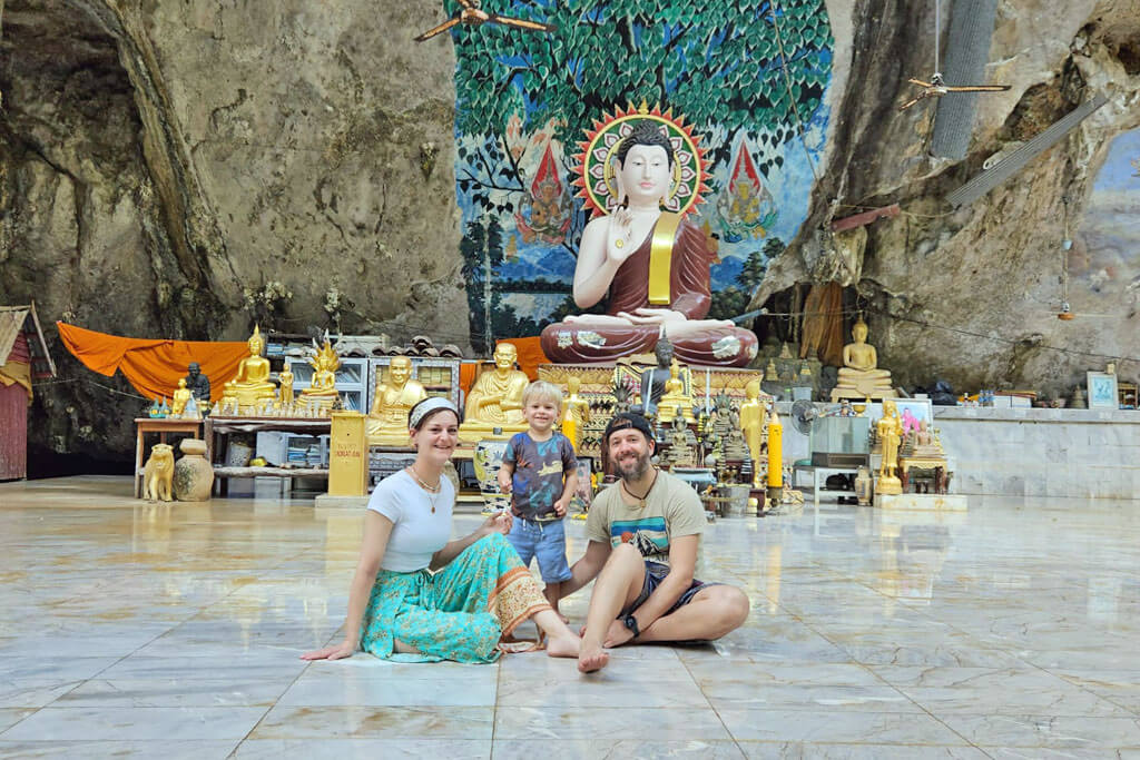 Eine Familie vor einem Buddha-Altar vor einer Felswand