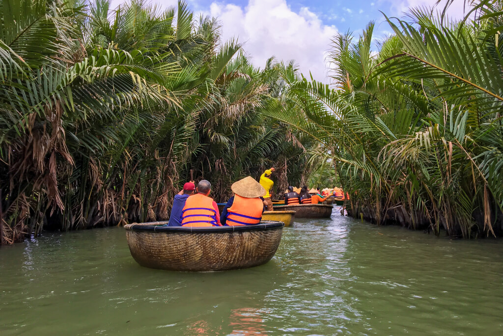 Touristen mit orangenen Schwimmwesten fahren Bamboo Basket Boat in Hoi An