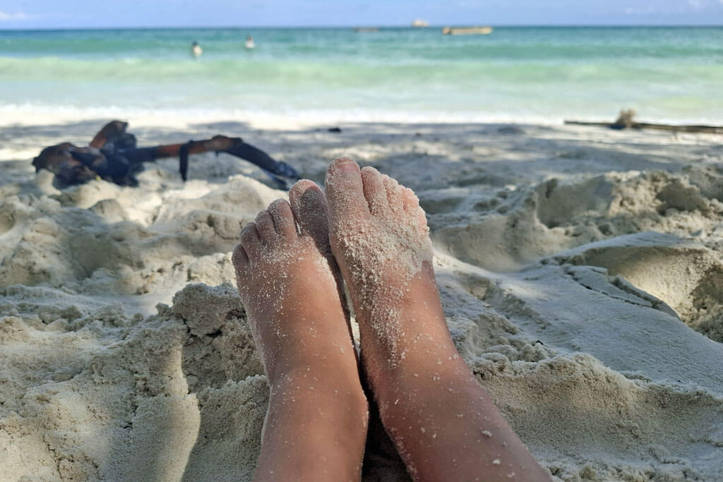 Kleine Kindefüße im Sand, dahinter das Meer