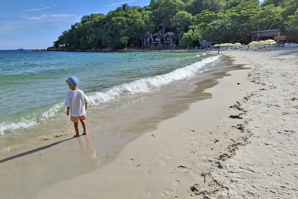 Ein Kind mit Mütze und Shirt am Strand