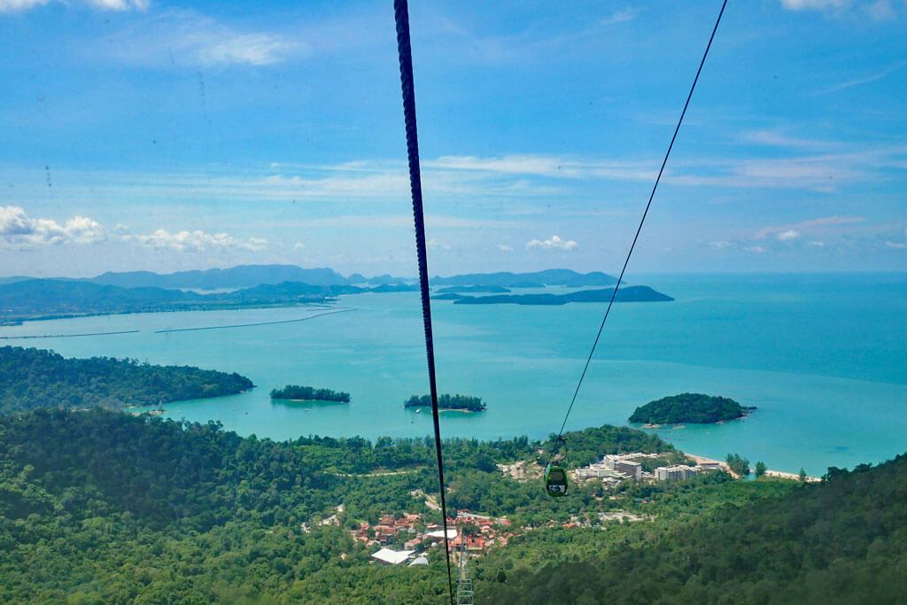 Blick aus der Seilbahn auf Langkawi auf grünen Dschungel und die Inselküste sowie türkisfarbenes Meer mit vorgelagerten Inseln