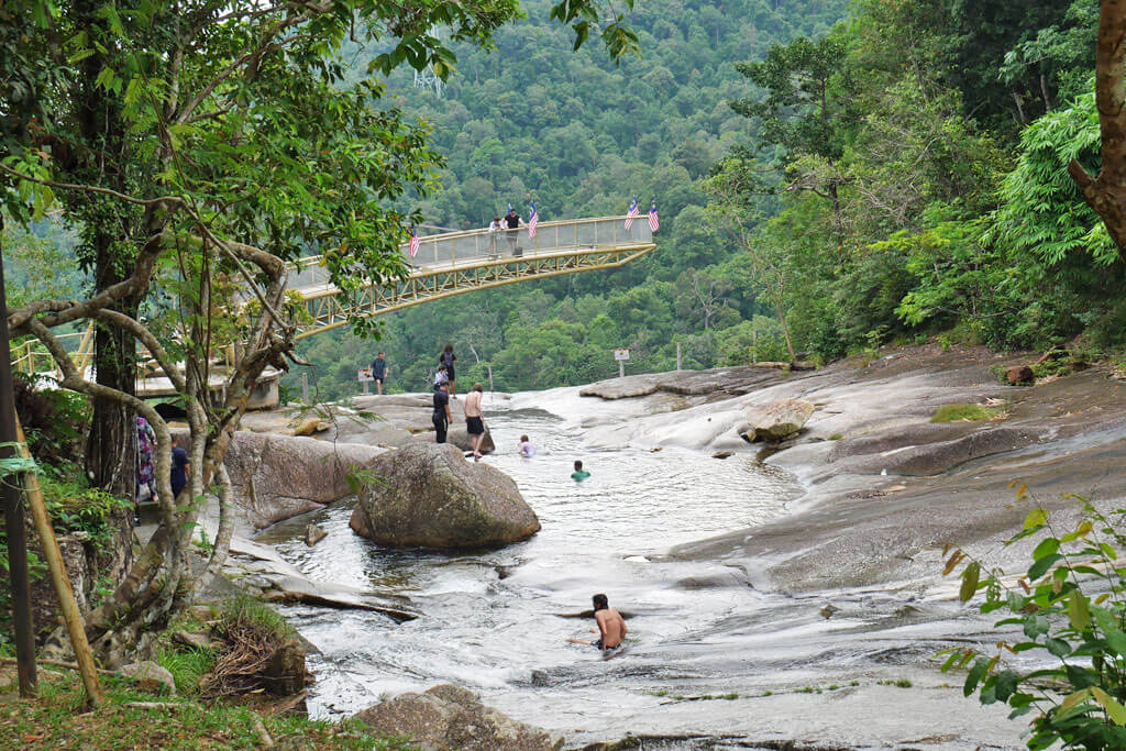 Touristen baden in den natürlichen Badepools am Wasserfall auf Langkawi, Malaysia