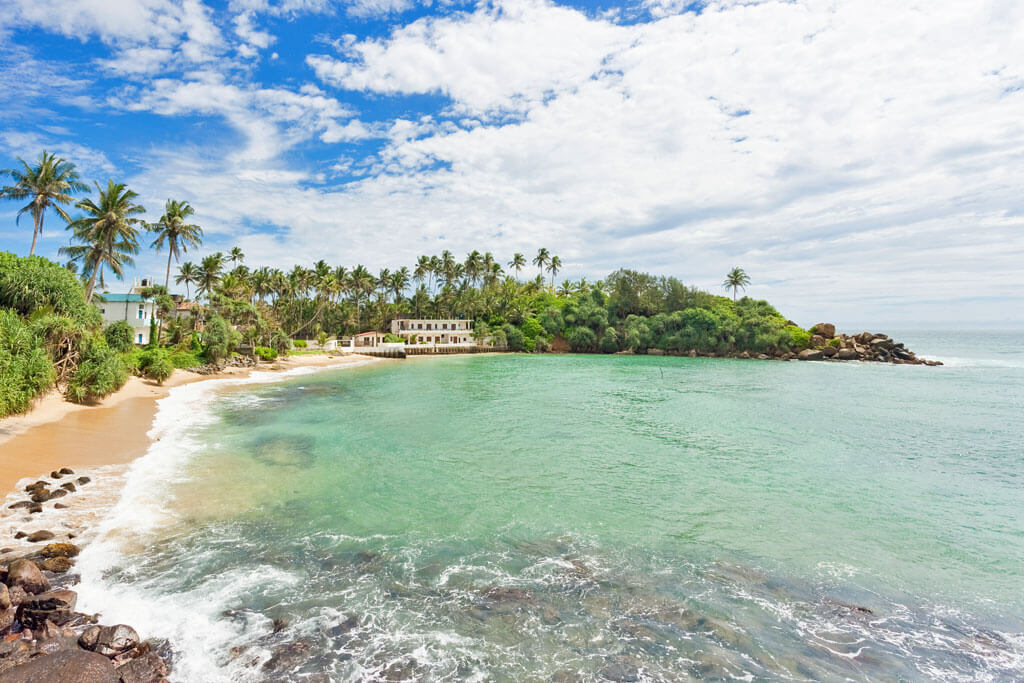 Ein Strand mit türkisblauem Meer, Wellen und Palmen