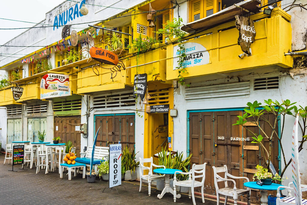 Ein gelbes Gebäude mit Tischen und Stühlen davor dient als Restaurant