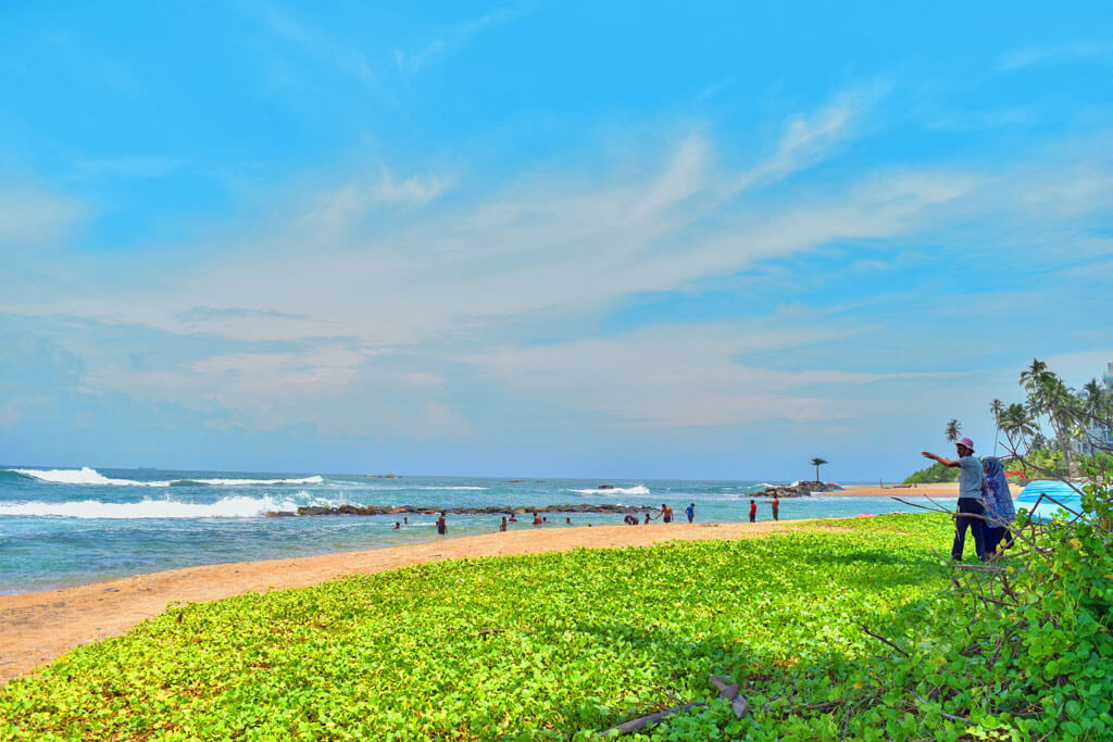 Ein naturbelassender Strand mit Fischern, Wellen und Pflanzen