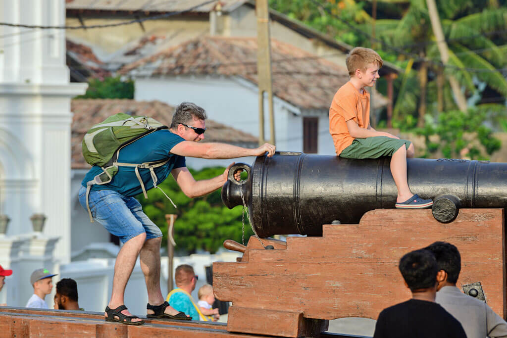 Ein Kind sitzt auf einer Kanone, der Vater sorgt dahinter für Spaß