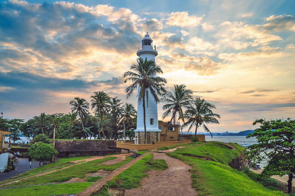 Ein Leuchtturm umringt von Palmen bei Sonnenuntergang