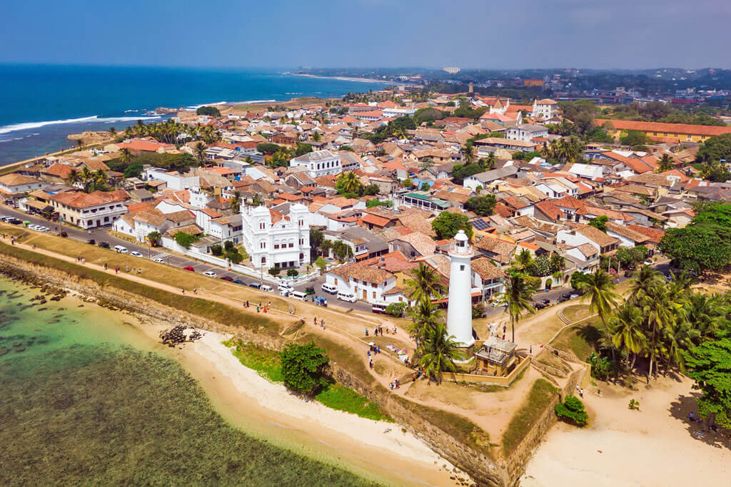 Luftaufnahme auf eine historische Stadt mit Leuchtturm an der Küste