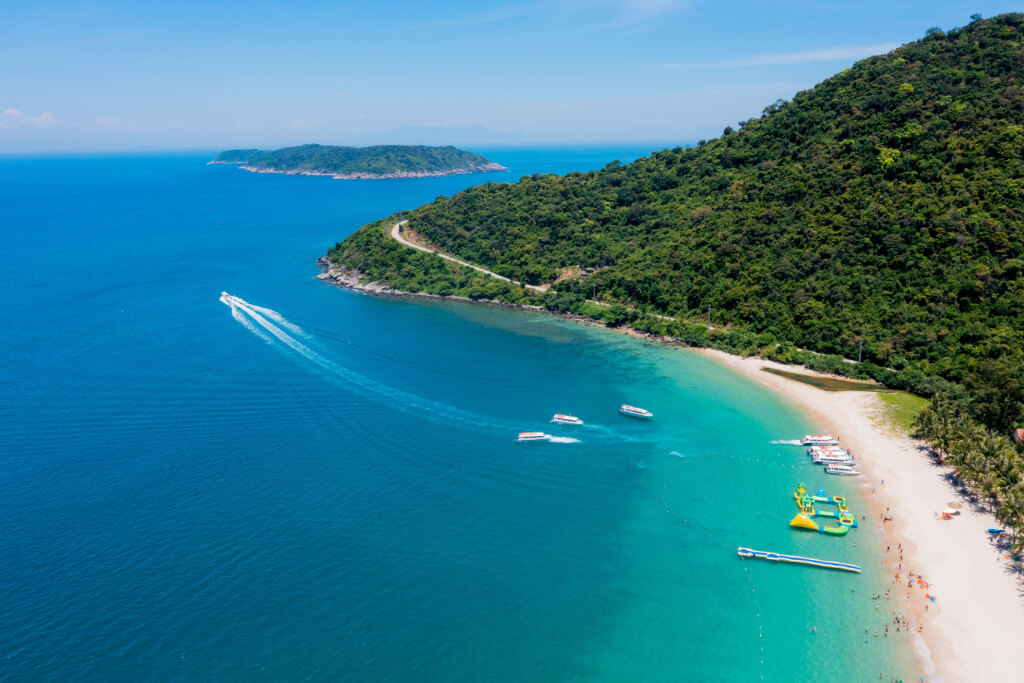 Luftbild des Hauptstrandes von Cham Island, an dem einige Speedboote liegen