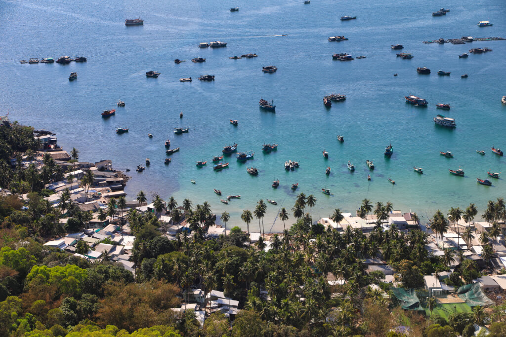 Fischerdorf auf Nam Du von einem Hügel aus gesehen, im Hintergrund viele Fischerboote auf dem Meer