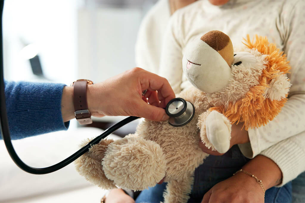 Eine Hand hört mit einem Stethoskop die Herztöne eines Kuscheltiers ab