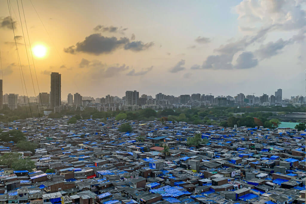 Aussicht auf die Slums von Mumbai mit unzähligen Wellblech-Dächern bei Sonnenuntergang