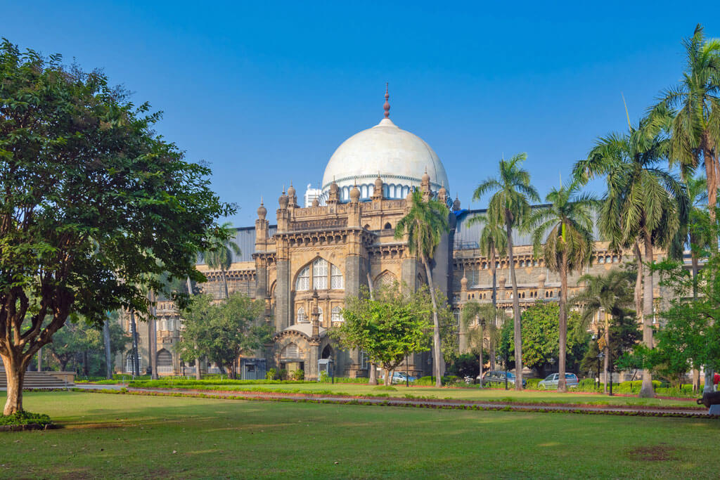 Ein schönes Gebäude aus der Kolonialzeit mit großer Kuppel, davor Palmen