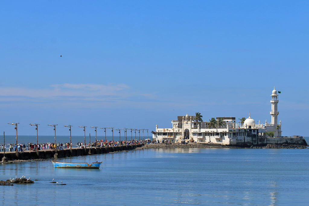 Menschen laufen auf einem Weg über das Meer zu einer Moschee auf einer Insel