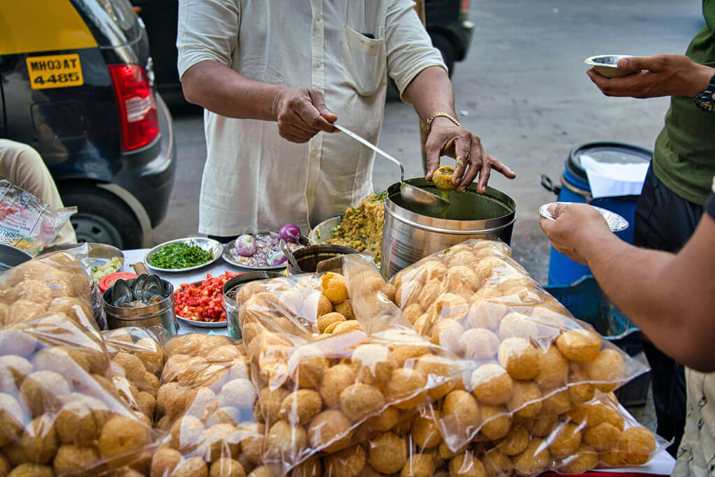Ein Mann bereitet frisches Pani Puri zu und verkauft es auf der Straße an Kunden
