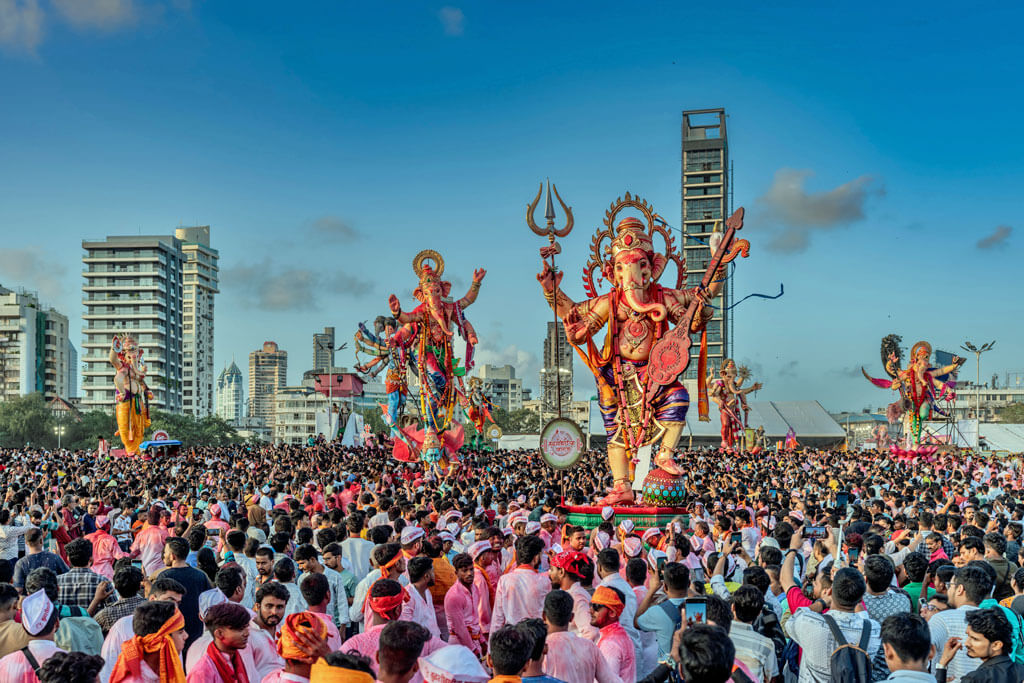 Eine Menschenmenge, darin werden hinduistische Götter-Statuen hochgehalten